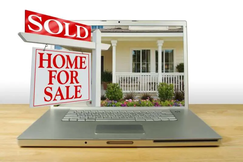 computer with home sale sign